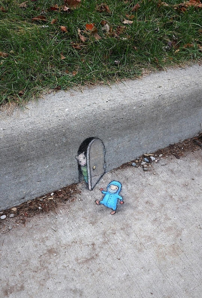 Streetart. Two small mice have been painted with chalk on and along a sidewalk. A mouse with a door is painted on the curb. It wears a green dress and looks cautiously out of the door. Another mouse is standing on the sidewalk in front of it. She is wearing a sky-blue full-body romper suit with a hood, a scarf over her mouth, gloves and warm shoes. She stumbles awkwardly towards the door. It seems to be getting very cold? Title: "There are people who own snowsuits."