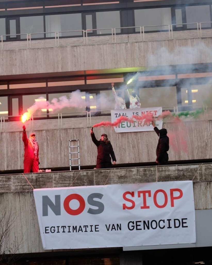 Foto van het NOS-gebouw met activisten op het balkon met flares. Twee banners met de teksten: 'TAAL IS NIET NEUTRAAL' en 'NOS STOP LEGITIMATIE GENOCIDE'. 