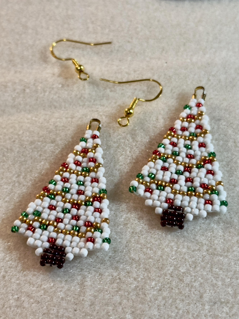 A pair of Christmas tree beaded earrings in progress on a bead mat