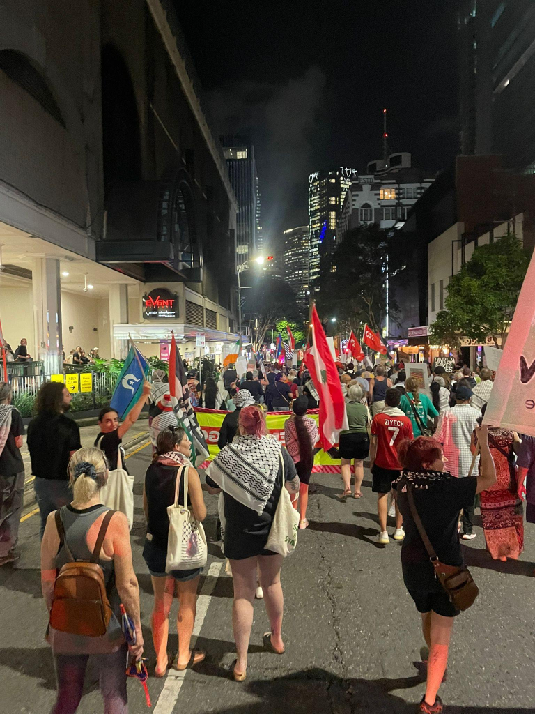 People marching with Lebanese and Palestinian flags (also a Torres Strait Islander flag)