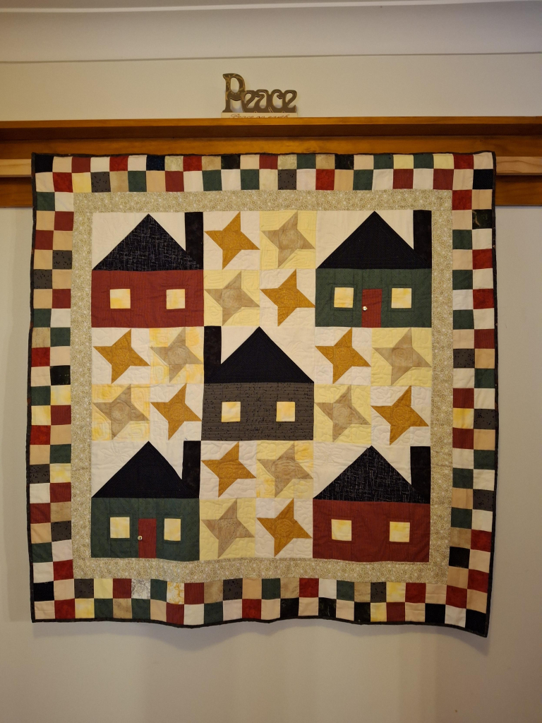 AFive little quilt3d houses surrounded by stars