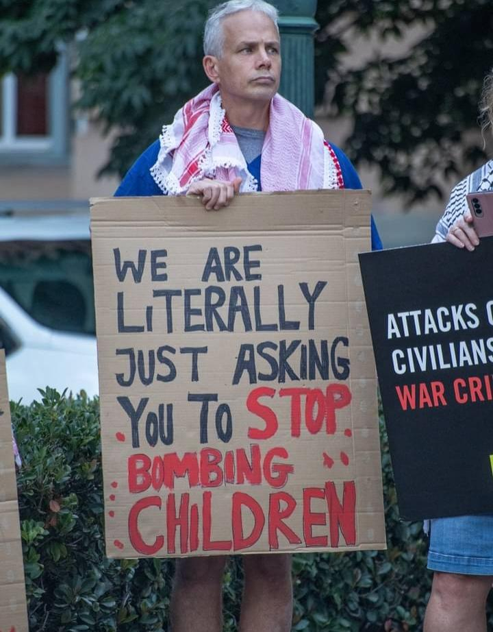 A sign that reads: "we're literally just asking you to stop bombing children"