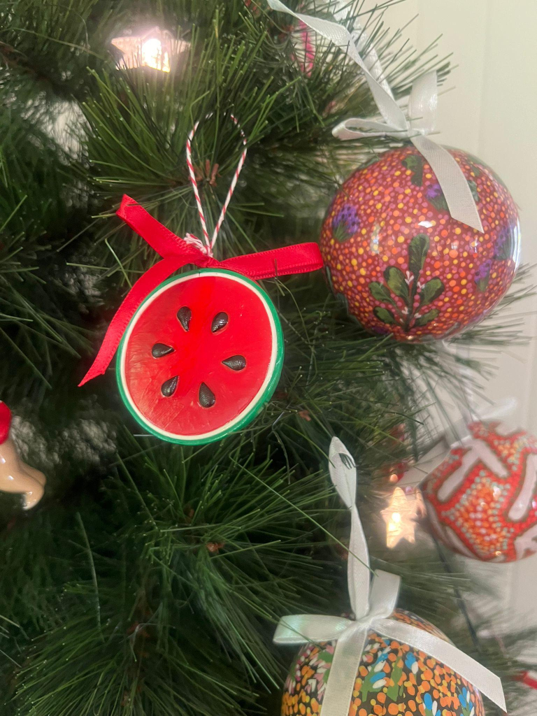 One of the decorations attached to the Christmas tree beside other Christmas baubles with aboriginal designs