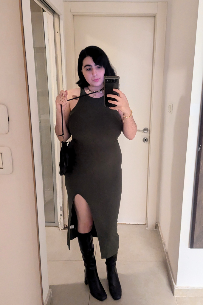 A mirror selfie of me in black high heels and a tight olive green dress with a split of it on my left leg.