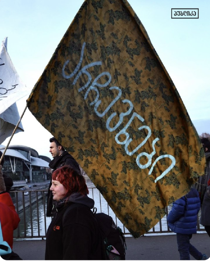 Painters march in Tbilisi, Georgia with a flag that says in Georgian, 'Elections'