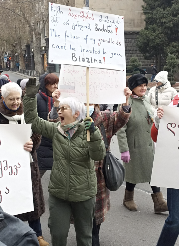 Grandparents march in Tbilisi Georgia. A grandmother is holding a sign saying 'The future of my grandkids can't be trusted to you, Bidzina!'