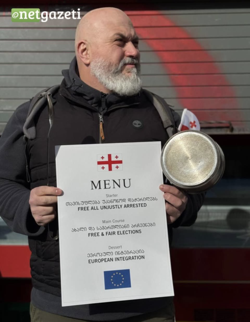 Georgian chef at a protest in Tbilisi, Georgia. Hes holding a menu that has the release of political prisoners, free and fair elections, and European Integration on it.