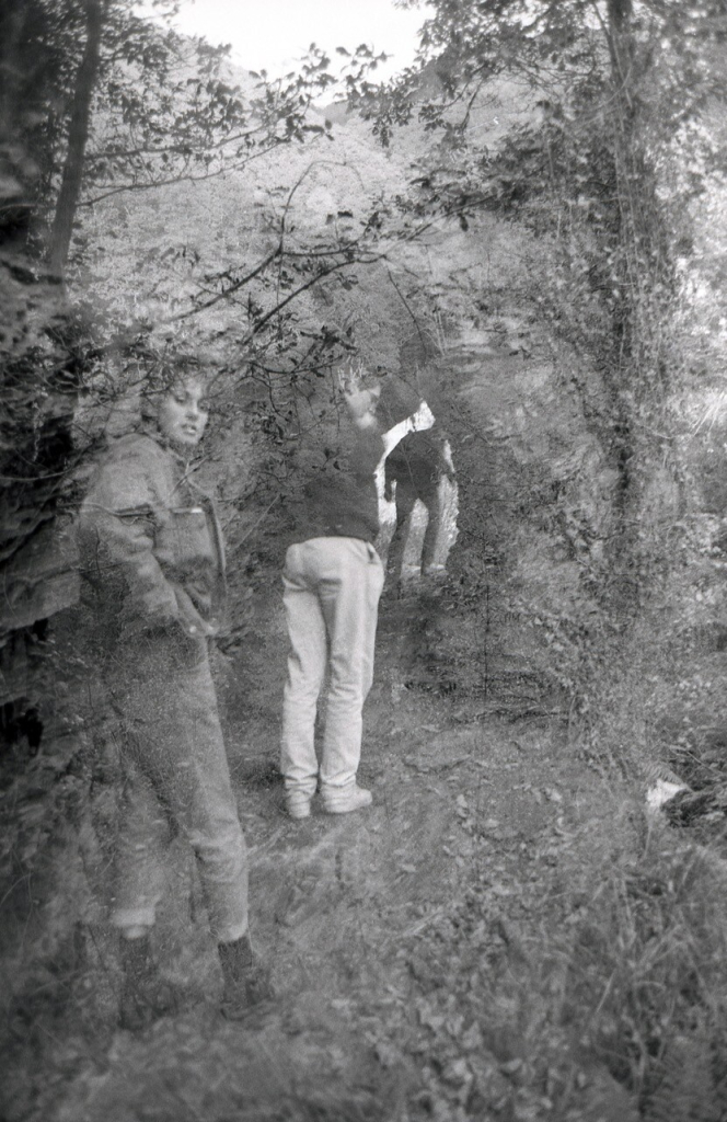 Black and white photograph. A double exposure of people hiking in the woods.