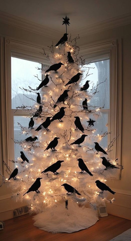 an all white christmas tree decorated with crows and a black star