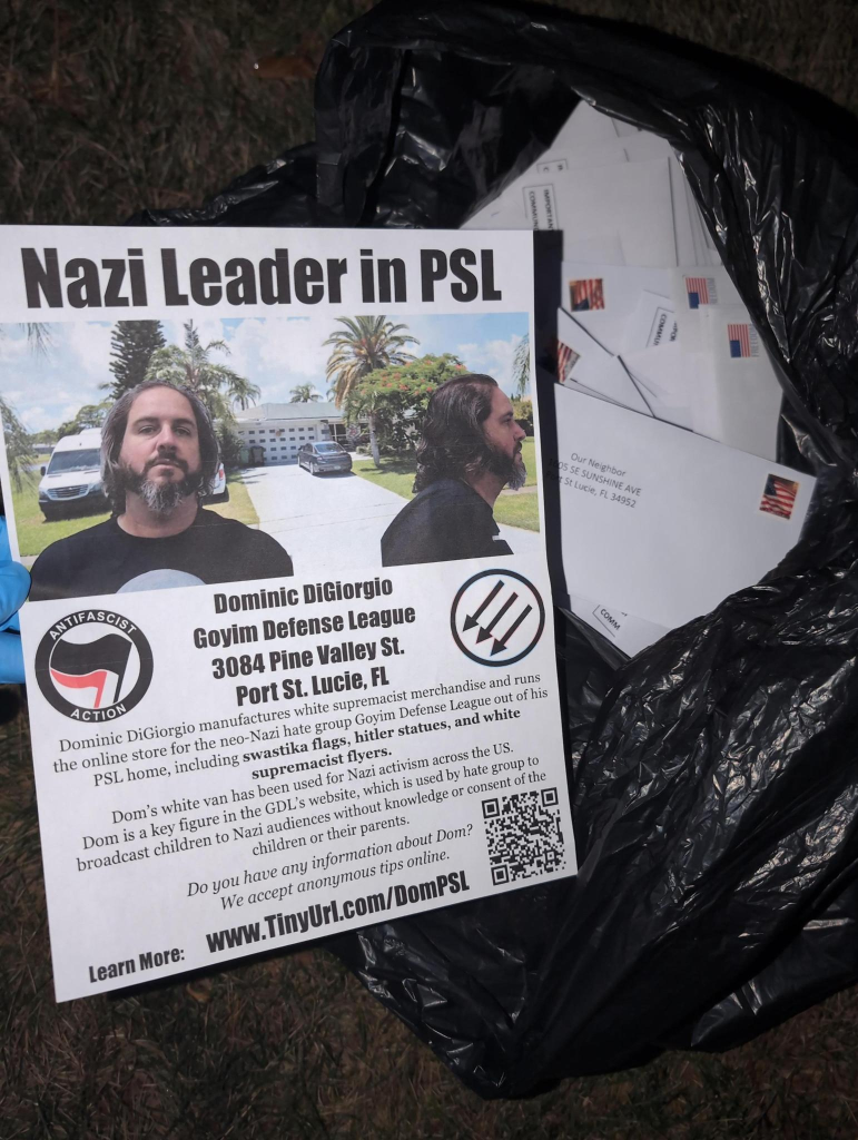 A flyer that says 

"Nazi Leader in PSL

Dominic DiGiorgio
Goyim Defense League
2084 Pine Valley St.
Port St. Lucie, FL"

The flyer has a photo of dominic digiorgio in front of a picture of his home. The flyer is on top of a garbage bag of envelopes.