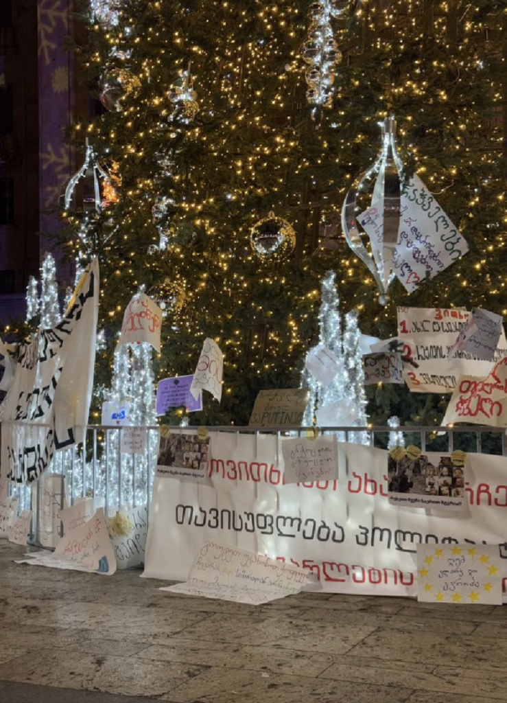 Christmas tree outside parliament in Tbilisi Georgia is decorated with many protest banners and signs.