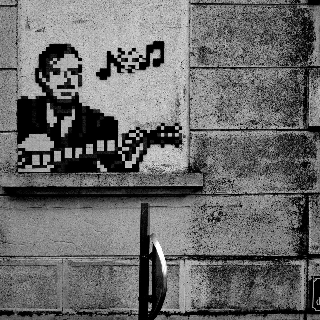 Photo d'une mosaïque posée sur une fenêtre murée par le street artist Invader représentant le musicien Django Reinhardt jouant de la guitare.