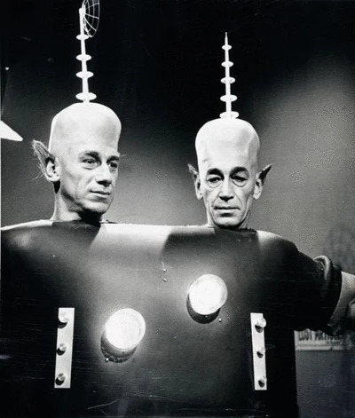 old science fiction movie with two dudes in a ridiculous costume -- elf ears, antenna coming out of their bald super-cranium, and flashing lights on t heir (shared) body