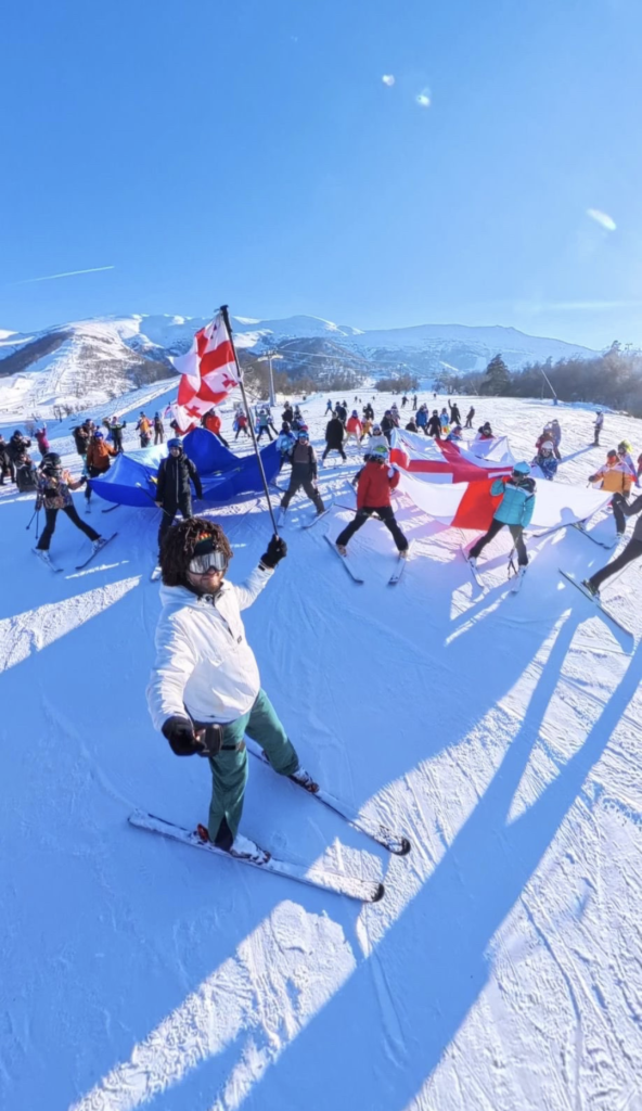 Skiers on a mountain in Georgia holding huge EU and Georgia flags 