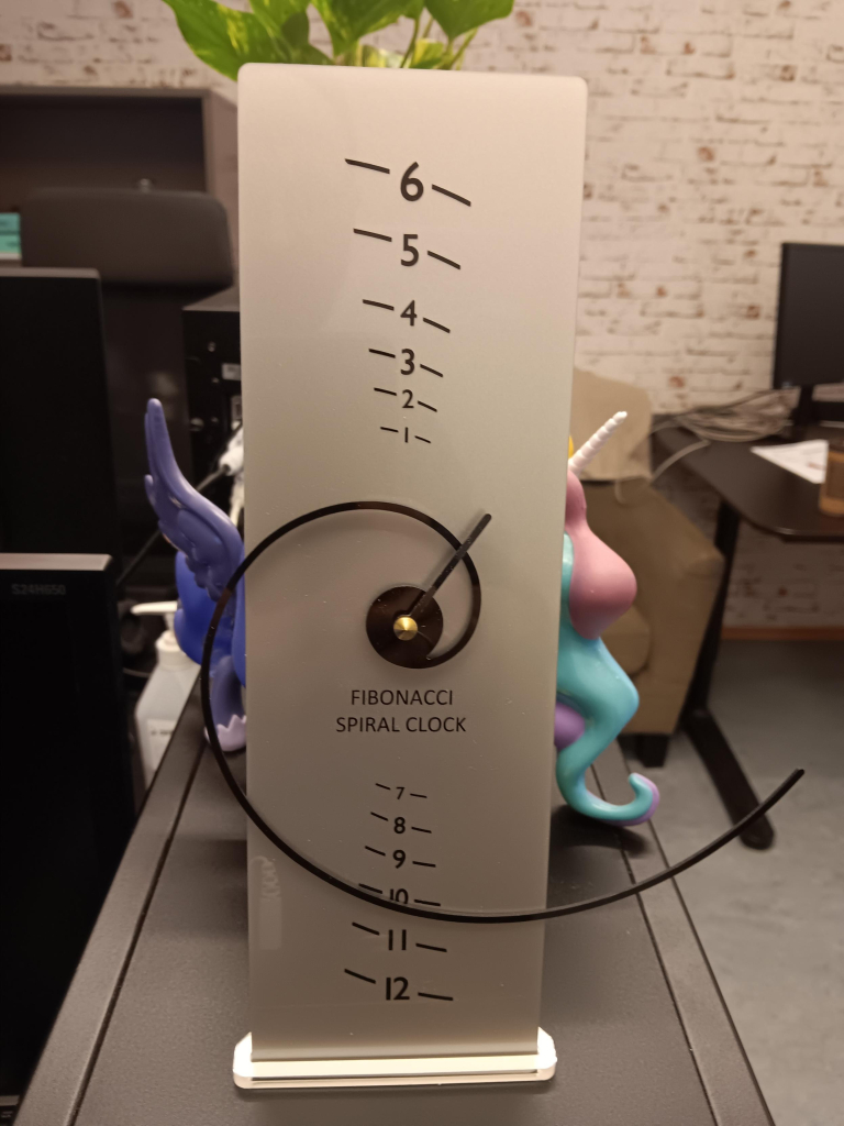 Fibonacci spiral clock. The hour hand is an expanding spiral that overlaps ever widening markers to represent hours. 