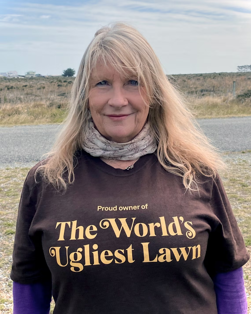 Photo of a woman in a 'proud owner of The World's Ugliest Lawn shirts and caption Leisa Elliott’s winning lawn is in Birdlings Flat in the Canterbury region of New Zealand. Photograph: Leisa Elliot