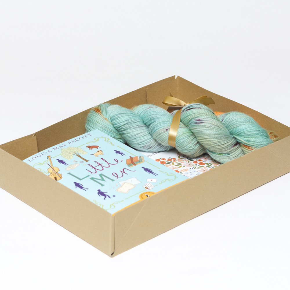 Picture shows an open A4 box containing yarn and a book.