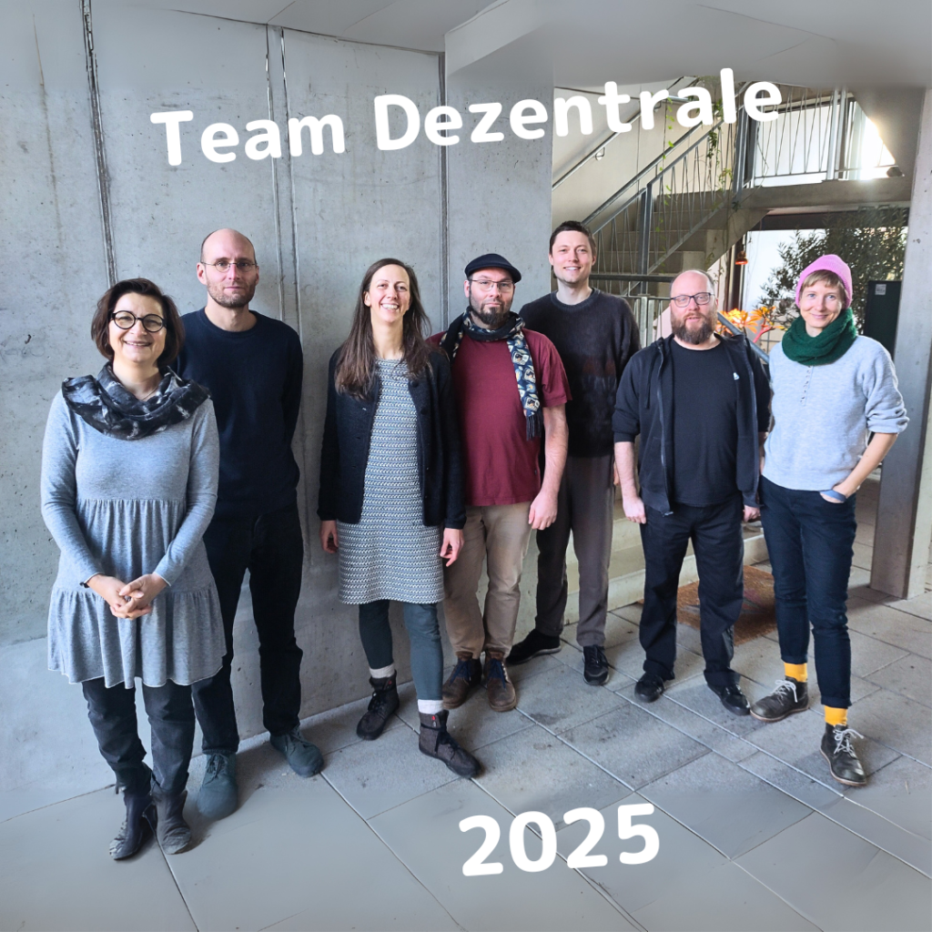 Das Bild zeigt sieben Personen, die das Team der Dezentrale Sachsen sind. Sie stehen in einer Reihe vor einer grauen Betonwand in einem modernen Gebäude. Über ihnen steht der Schriftzug „Team Dezentrale“, und unten im Bild ist die Jahreszahl „2025“ eingefügt. Im Hintergrund sind ein Treppenaufgang und ein Fenster mit etwas Grün zu erkennen.

Foto @ OurHouse eG Kooperatives Wohnprojekt im Leipziger Westen