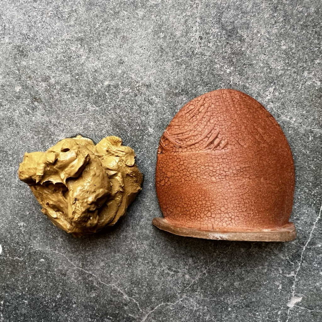 A lump of moist, tan clay (the same clay from the mine) next to an oval test tile showing what that same clay looks like when turned to terra sigillata,  brushed on top of commercial clay and fired to cone 5 (over 2100°F). The tile is a rich, brownish-orange color and has a cracked surface texture, kind of like aged leather. 