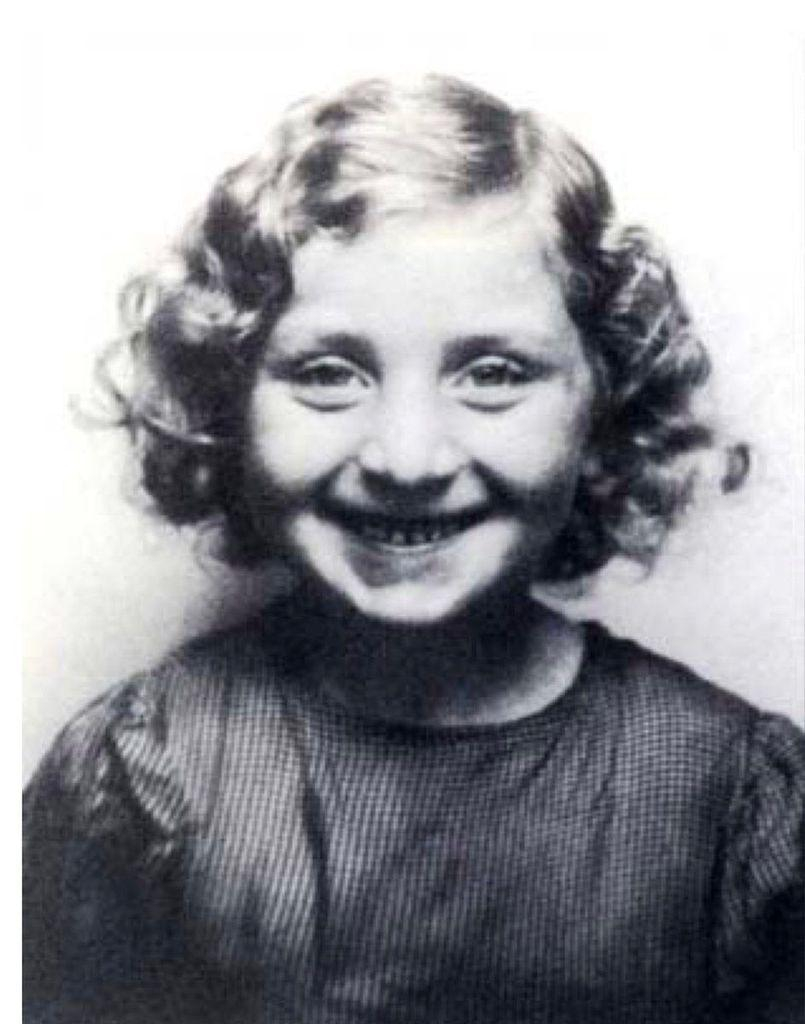 Vintage black and white portrait of a young girl smiling, with curly hair.