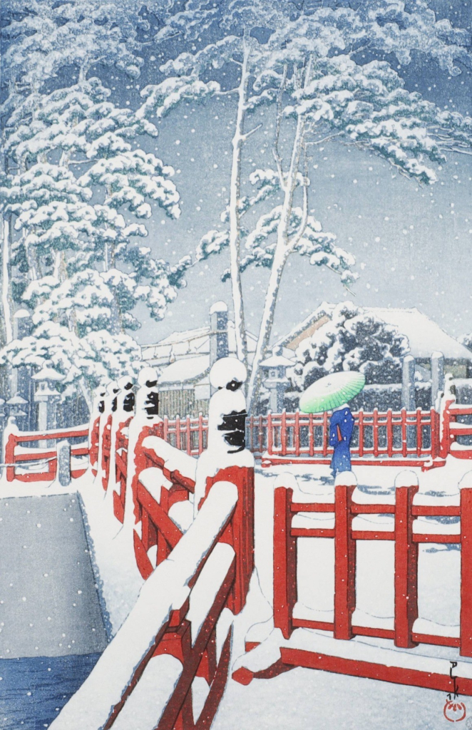 A snowy day in Nagata Ward, Kobe. A solitary figure carrying a bamboo umbrella crosses a red-laquered bridge; below, the cold-looking waters of the Karumo River slide past. On the far side of the bridge, tall wiry pine trees stand tall over neighbourhood houses. A layer of fresh snow covers the bridge railings, the ground, the rooftops of the houses, and clogs the branches of the trees. The sky above is dim and overcast, and snow continues falling across the scene.