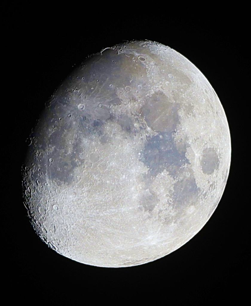 Abnehmender Mond, ca. 80%, vor schwarzem Hintergrund; durch Erhöhung der Farbsättigung werden in den Maren bläuliche und grünlich-gelbe Flecken sichtbar, je nach Zusammensetzung der Lava, die nach dem Einschlag großer Meteorite hochgequollen ist und die Flächen ausgefüllt hat.