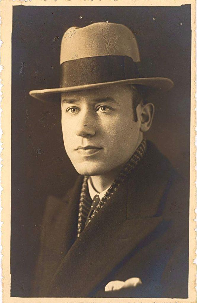 Vintage portrait of a man wearing a bowler hat and a patterned scarf, with a solemn expression.