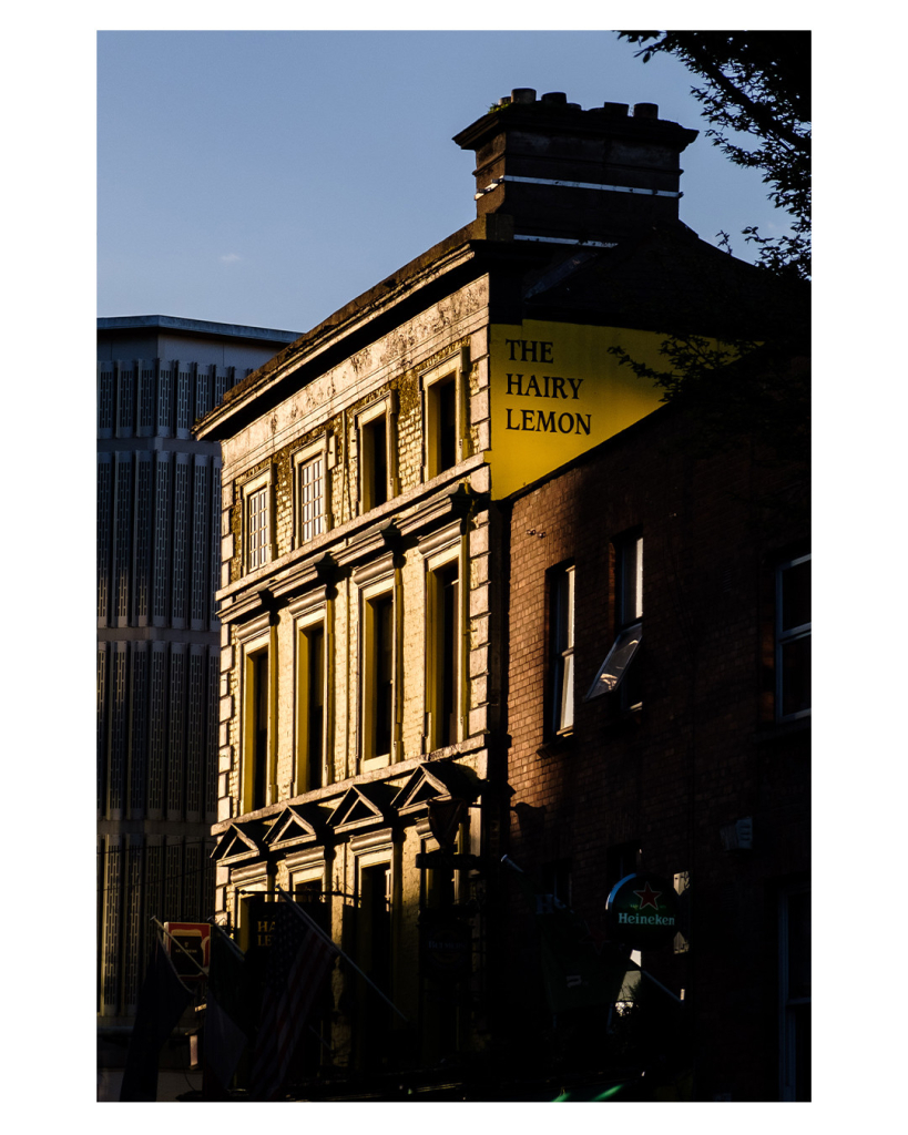 Foto im Hochformat. Ein altes gelbliches Gebäude. Auf der Seite steht „The Hairy Lemon“. Das Gebäude wird von der Abendsonne angestrahlt, alles andere im Bild versinkt im Schatten. 