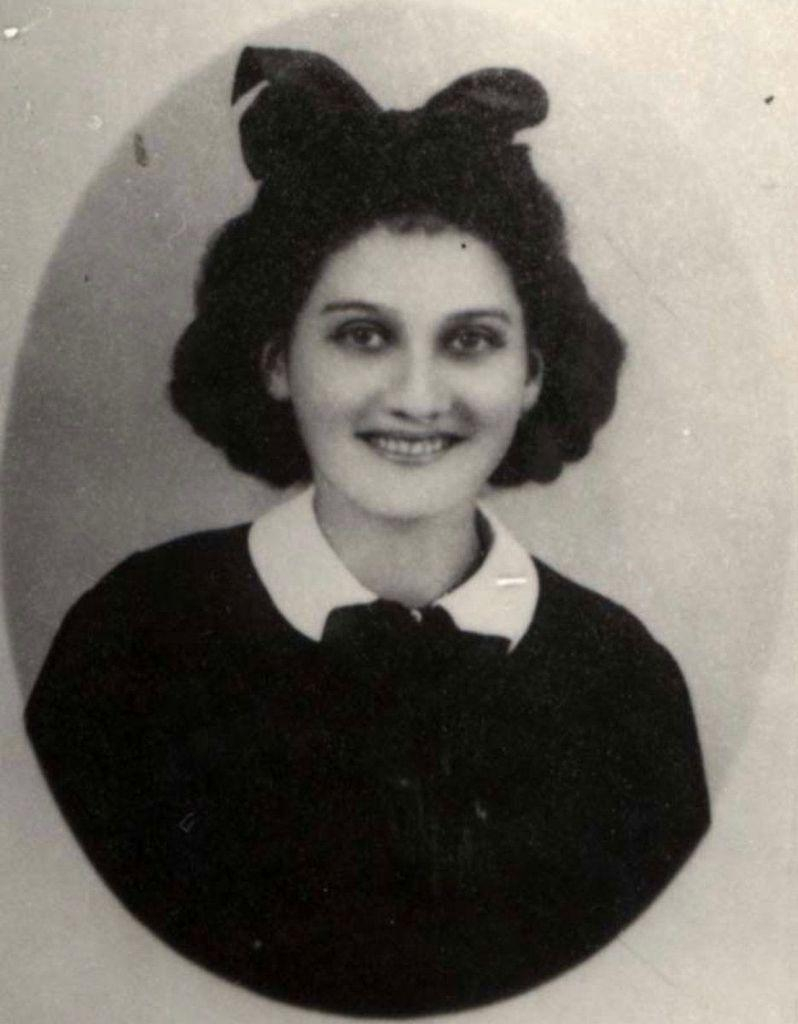 Black and white portrait of a girl with a bow in their hair, wearing a collared shirt and sweater.