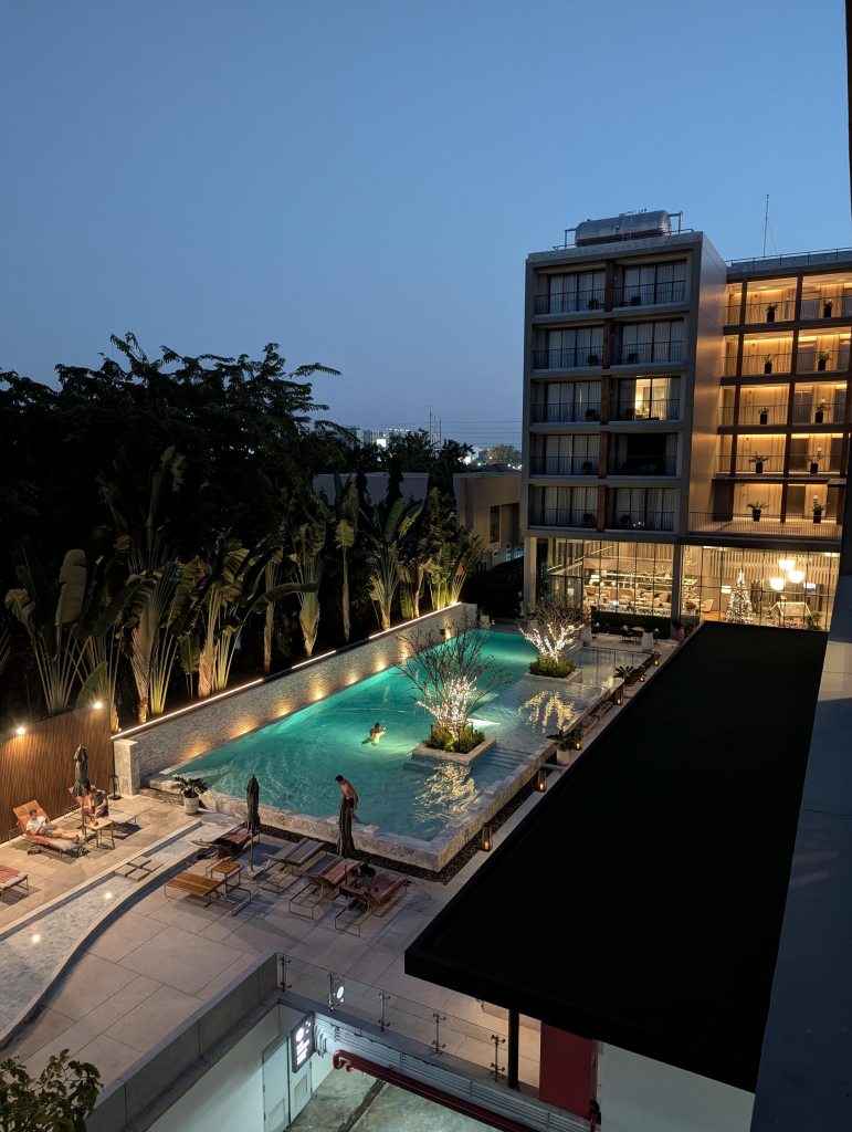 Photo of a hotel swimming pool and bar area from a 4th floor balcony.