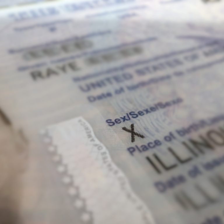 A close up photo of Raye's passport with focus blur highlighting the "X" marker listed for sex.