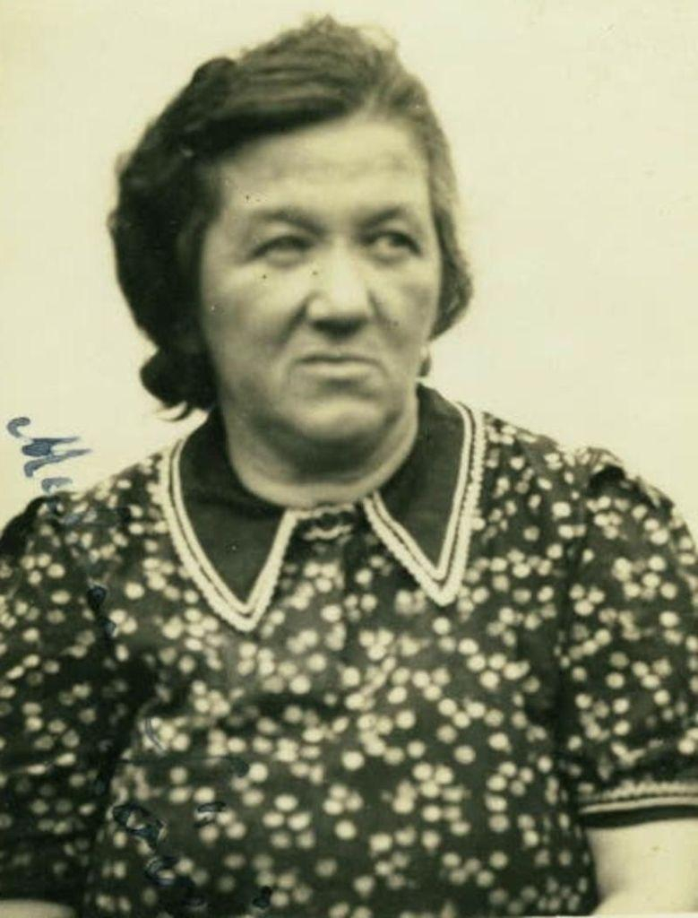 Vintage black-and-white portrait of a woman wearing a floral dress with a collared neckline, looking to the side.