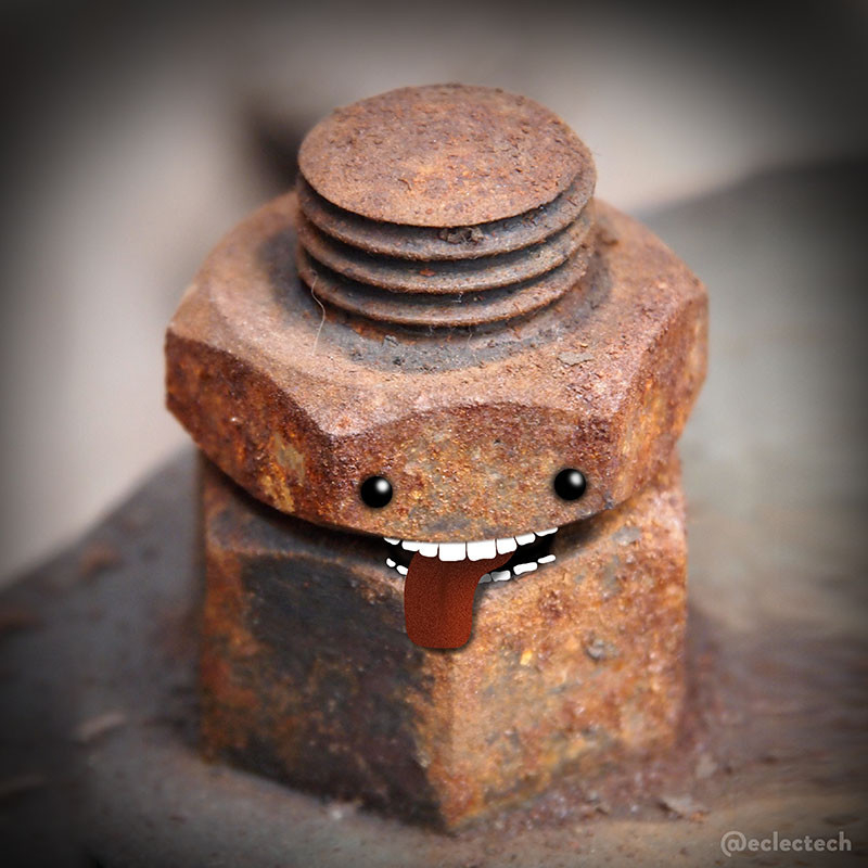 A square close up photo of a rusty old nut and bolt type thing (I'm not much of a DIY-er but I think that's what it is, it was taken in a Maritime Museum so was presumably once held bits of a ship together). The main body is hexagonal in two parts, I have presented the split between the two parts as a mouth, added teeth and a lolling out tongue, and added eyes above. The bolt sticks out through the top, like an odd little round hat with lines running round it.