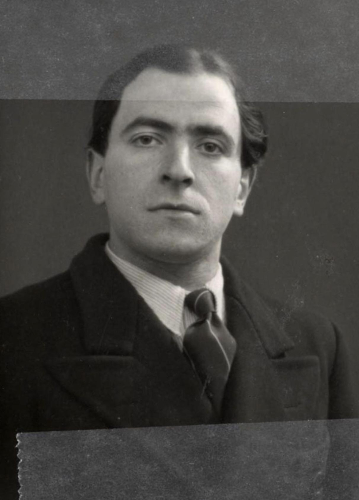 Black and white portrait of a man wearing a dark coat and tie.