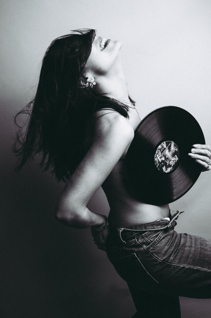 Mujer con el pelo delante de la cara y vinilo en la mano.