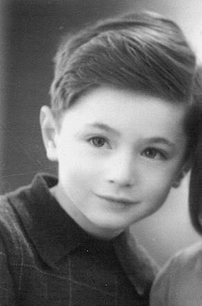 Black and white portrait of a young boy with neat hairstyle and a collared shirt, looking slightly to the side with a gentle expression.