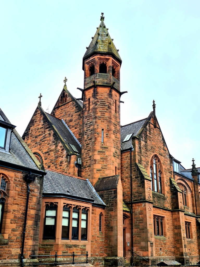 An impressive red sandstone church with a narrow, but relatively tall, central tower.