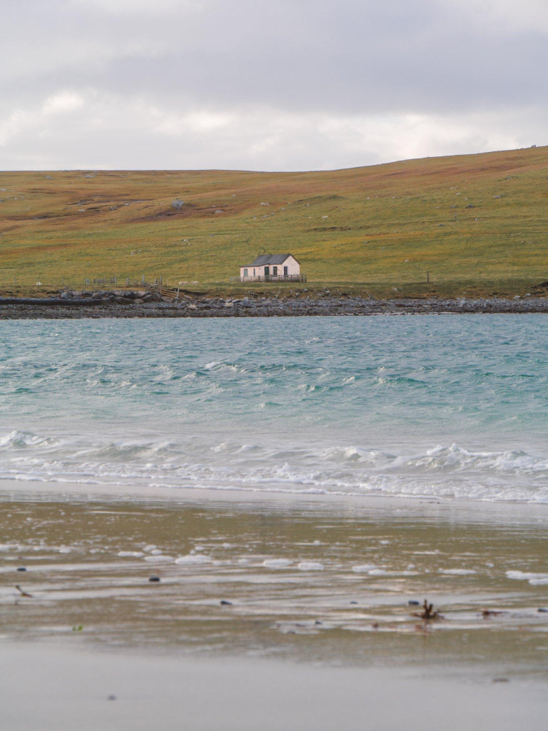 A white cottage on the other side of a relatively quiet body of water.