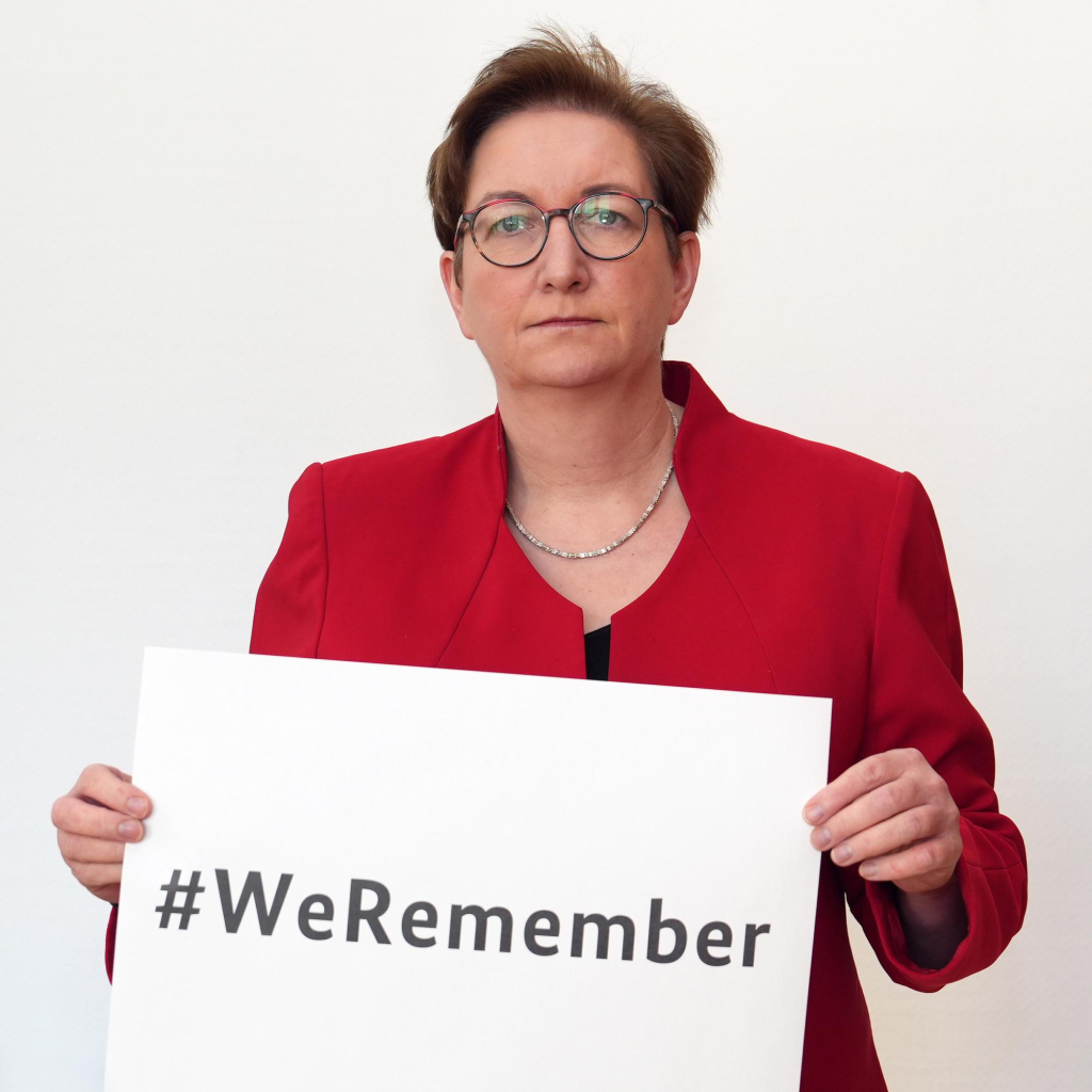 Bundesbauministerin Klara Geywitz hält ein Papierschild mit dem Hashtag #WeRemember in der Hand.