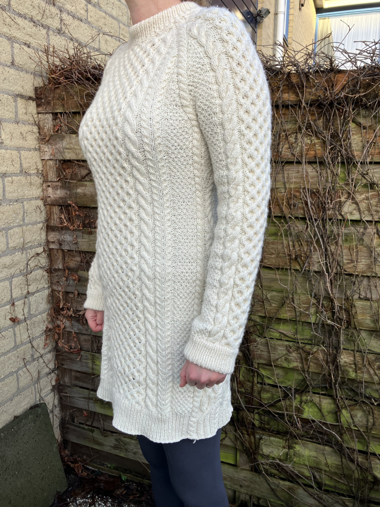 Woman in a cream knit cable dress coming to half thigh