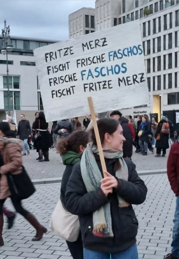 Demonstrantin mit Schild, Fritze Merz fischt frische Faschos Frische Faschos fischt Fritze Merz