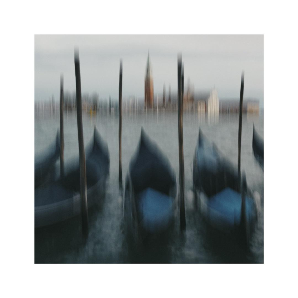 a slightly blurry view of some venetian gondolas dancing on the gentle waves. far in the background there‘s san giorgio maggiore