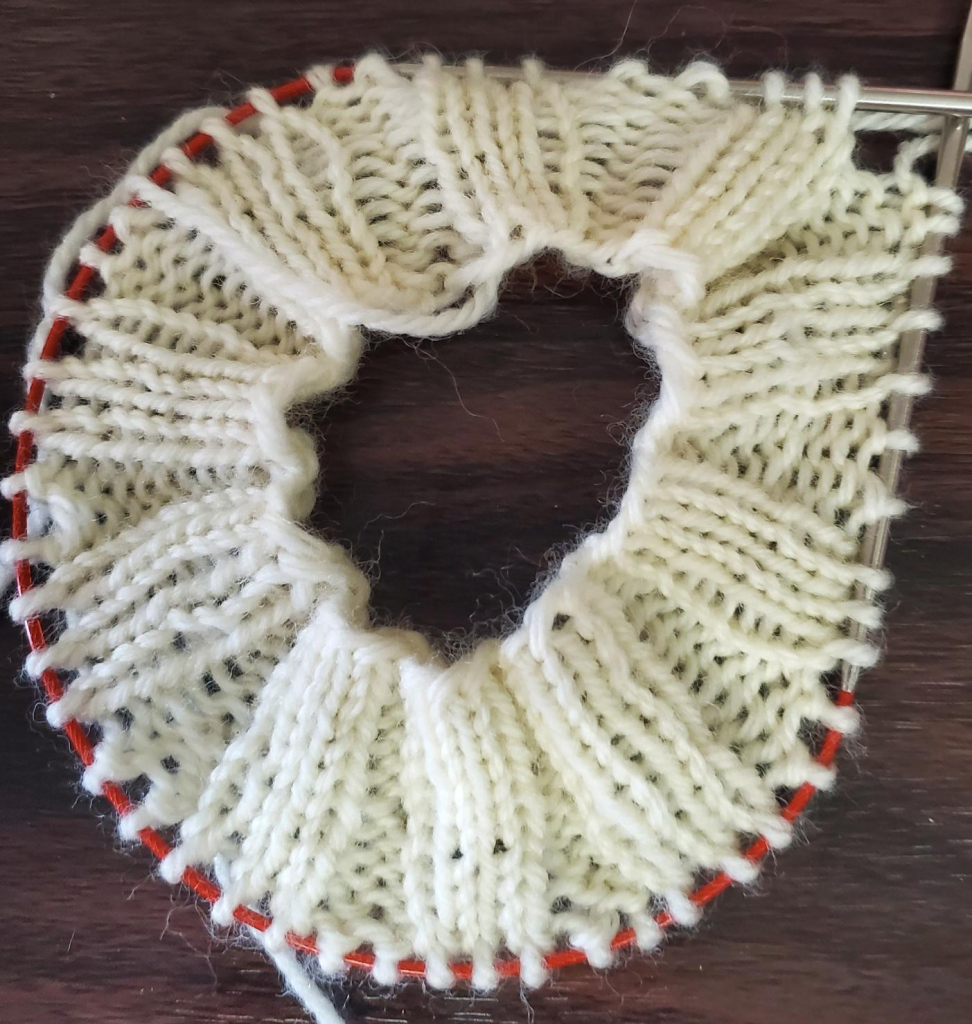 White yarn on 16" circular needle in 3/2 rib