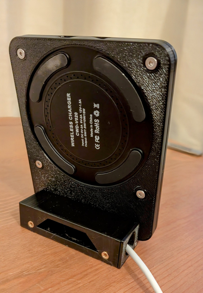 The back of the Qi Charger Stand. Assembled with four parts (foot with a cable door, stand with backplate and front cover).