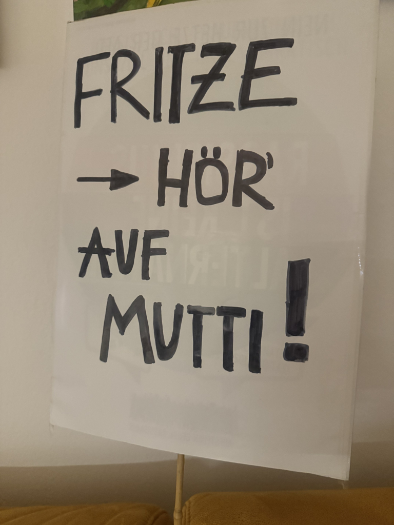 Demo-Plakat mit der Aufschrift 

FRITZE
→ HÖR
AUF
MUTTI!