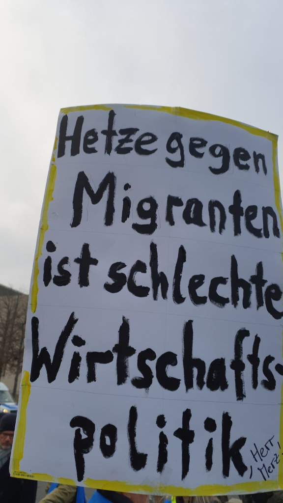 Demoplakat mit der Aufschrift "Jetzt gegen Migranten ist schlechte Wirtschaftspolitik"