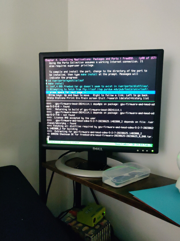 My Dell monitor showing my FreeBSD session with Tmux running in 2 panes, one over the other. Top pane is running Lynx browser and showing the Ports page on the FreeBSD Handbook. Bottom pane is building he dependencies for the drm-kmod port.