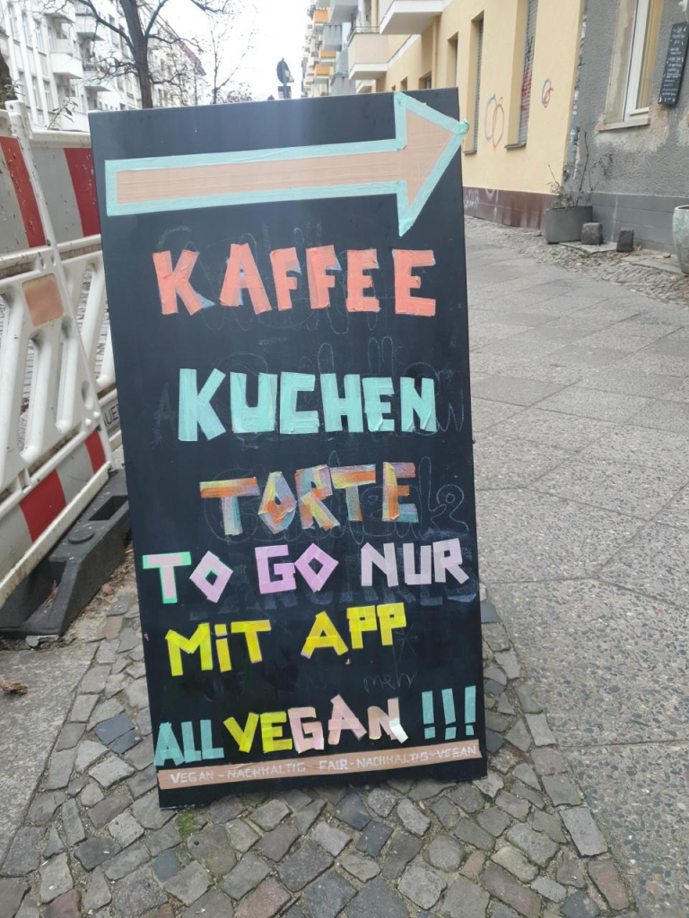 Aufsteller vor Geschäft mit dem Text:
Kaffee und Kuchen Torte to go nur mit App, all vegan.