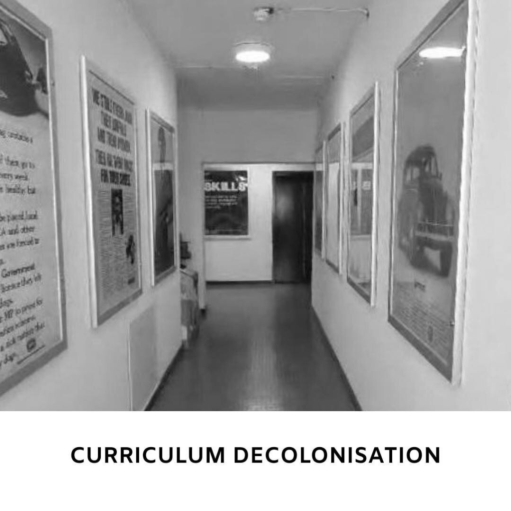 Black and white picture of a corridor with old style posters on the walls.