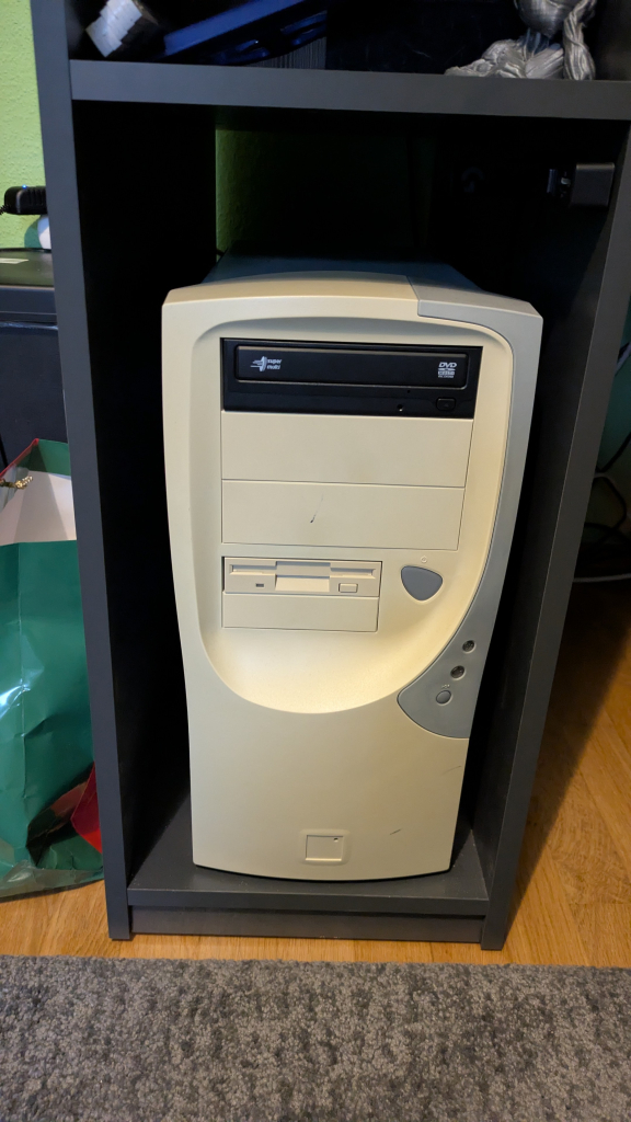 Ein Computergehäuse aus den 1990ern in Beige mit grauen Zierapplikationen.

Der DVD Brenner ist mit schwarzer Frontblende und es fehlen USB-Anschlüsse an der Frontseite.

Es ist auch ein 3,5 Zoll Diskettenlaufwerk zu sehen, das mangels Anschluss auf dem Mainboard ohne Funktion ist.